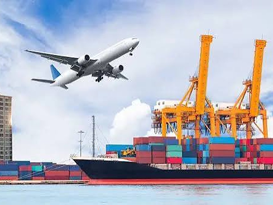 Container ship being loaded at a port terminal with a cargo aircraft overhead