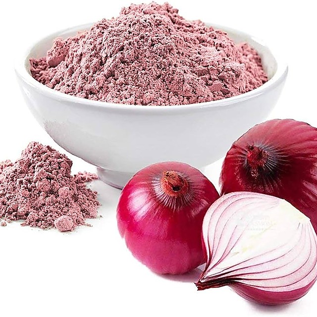 Bowl of red onion powder beside a whole and a halved red onion